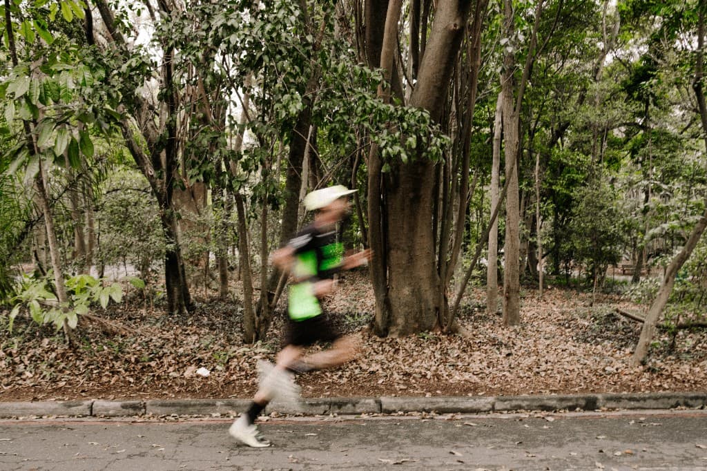 Corredor em movimento em trilha arborizada